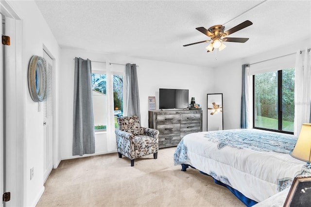 carpeted bedroom with multiple windows, a textured ceiling, and ceiling fan