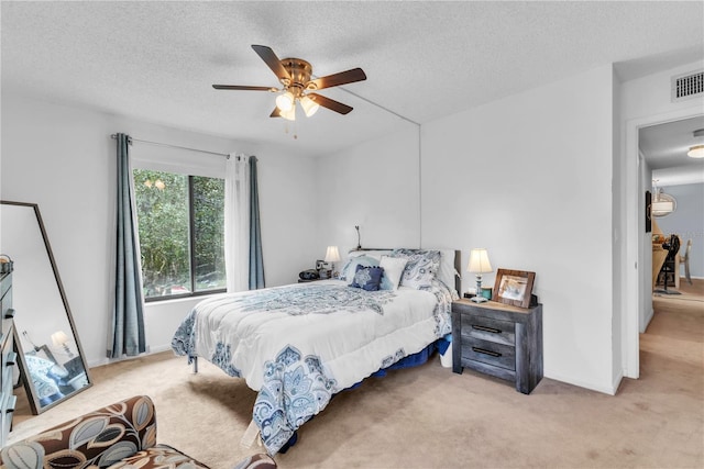 bedroom featuring ceiling fan, light colored carpet, and a textured ceiling