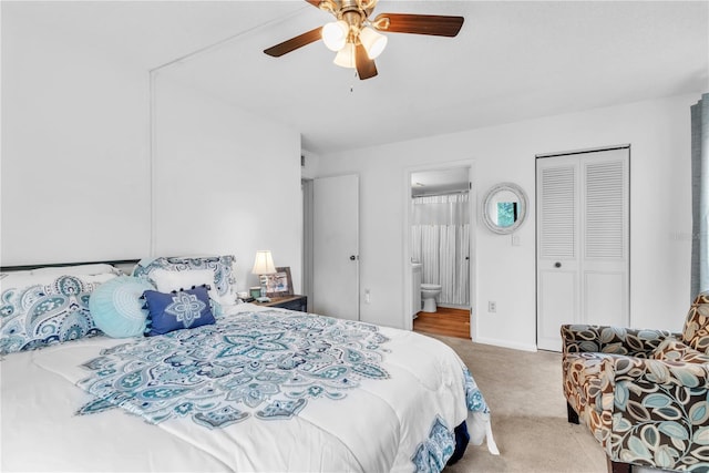 bedroom with ceiling fan, a closet, light colored carpet, and ensuite bath