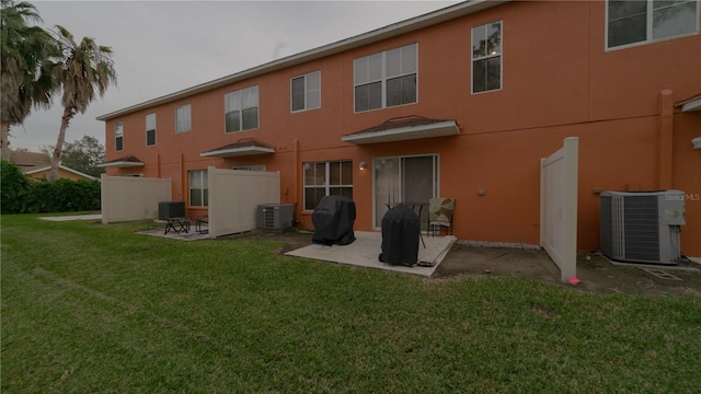 back of property with a lawn and central AC