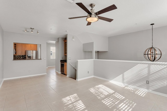 empty room featuring ceiling fan with notable chandelier, light tile patterned floors, and wine cooler