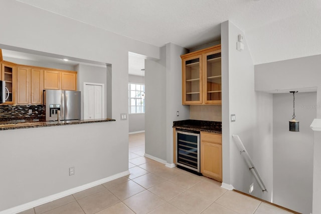 kitchen featuring dark stone counters, hanging light fixtures, wine cooler, stainless steel fridge, and light tile patterned floors