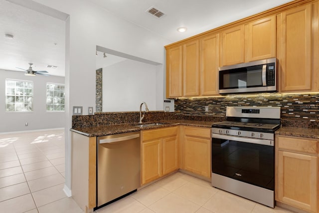 kitchen featuring dark stone counters, sink, ceiling fan, light tile patterned floors, and stainless steel appliances