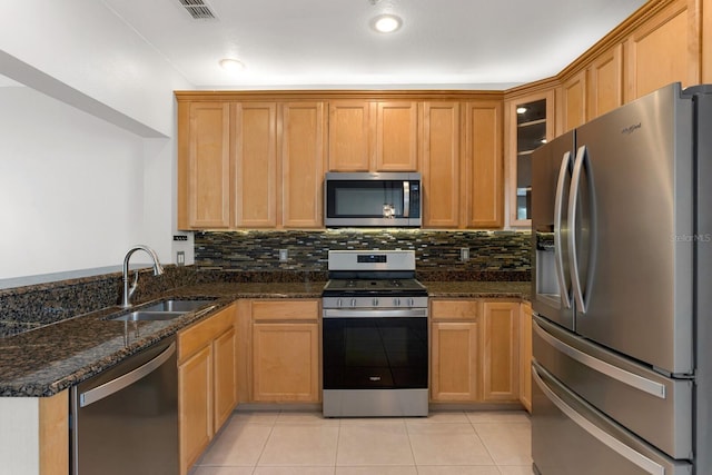 kitchen with sink, stainless steel appliances, kitchen peninsula, dark stone counters, and light tile patterned floors