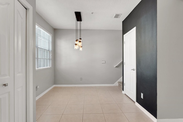 unfurnished dining area featuring a textured ceiling and light tile patterned flooring