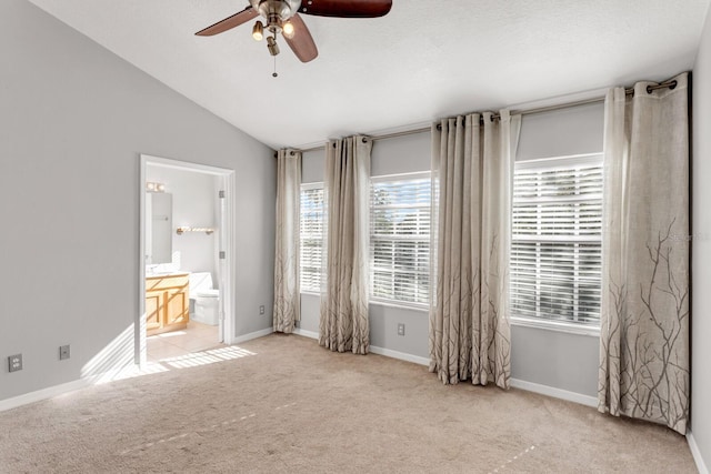 unfurnished bedroom featuring connected bathroom, light colored carpet, vaulted ceiling, and ceiling fan