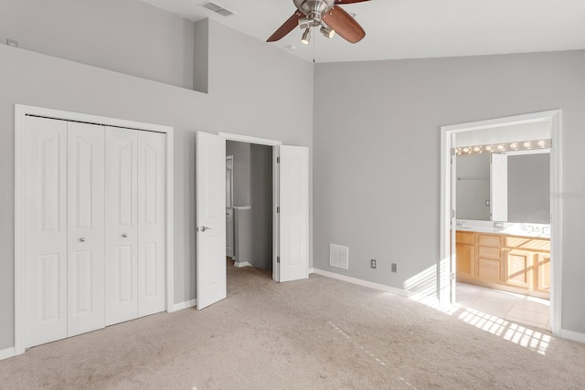 unfurnished bedroom with light carpet, ensuite bathroom, vaulted ceiling, ceiling fan, and a closet