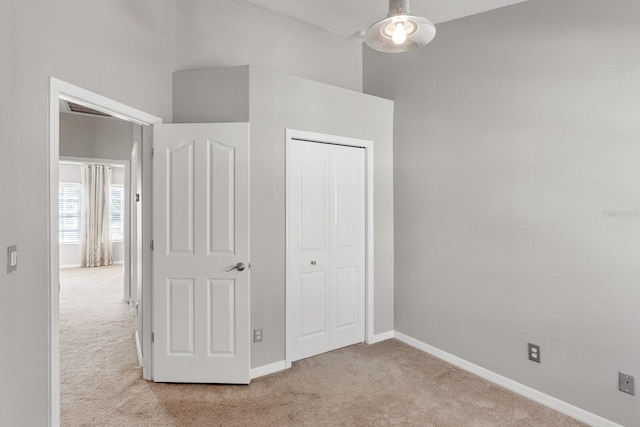 unfurnished bedroom featuring light colored carpet and a closet