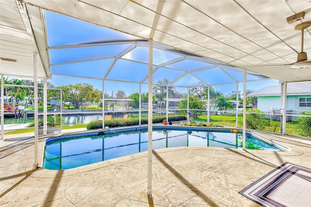 view of pool featuring glass enclosure, a patio area, and a water view