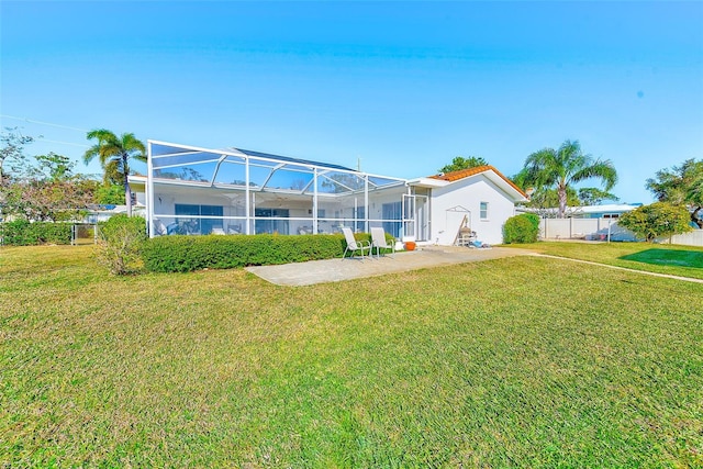 rear view of house with a lawn, glass enclosure, and a patio area