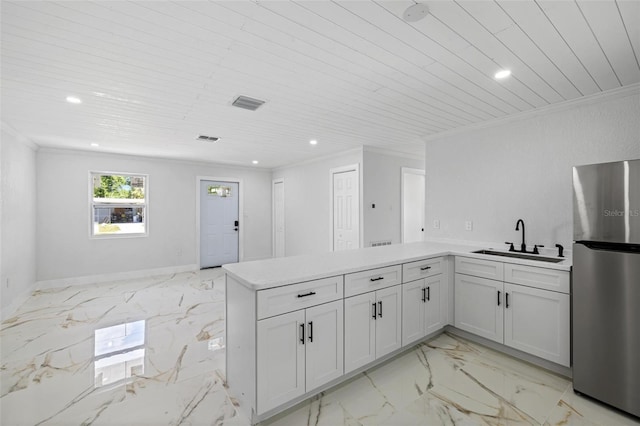 kitchen featuring kitchen peninsula, white cabinetry, sink, and stainless steel refrigerator