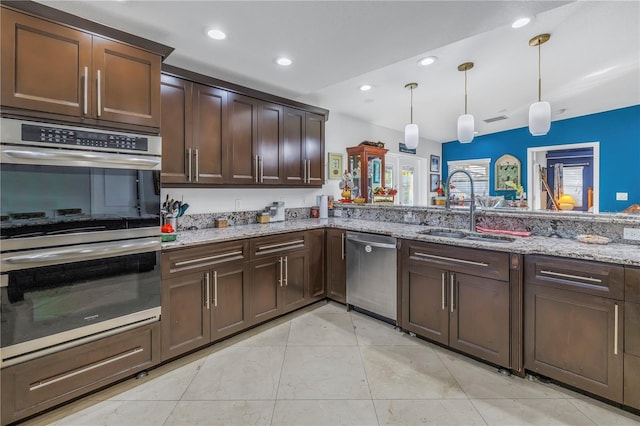 kitchen featuring light stone countertops, sink, pendant lighting, dark brown cabinets, and appliances with stainless steel finishes