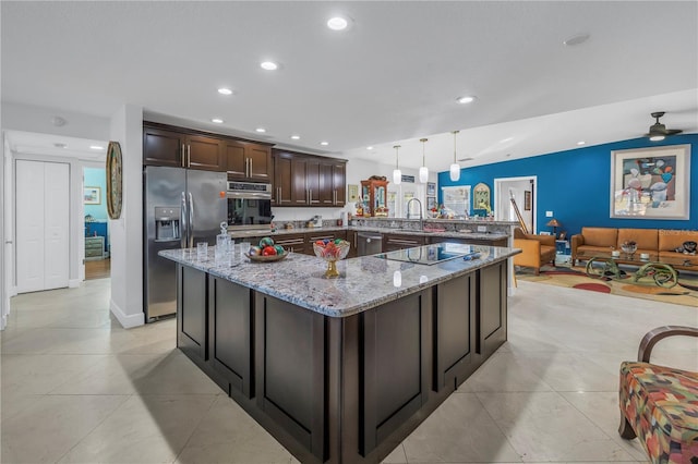 kitchen featuring pendant lighting, sink, light stone countertops, appliances with stainless steel finishes, and dark brown cabinetry