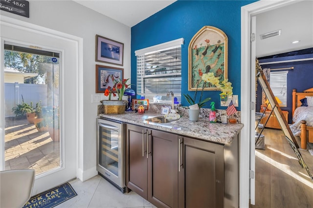 bar with a wealth of natural light, dark brown cabinetry, sink, and beverage cooler