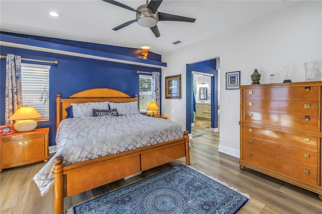 bedroom featuring hardwood / wood-style floors, ceiling fan, vaulted ceiling, and ensuite bath