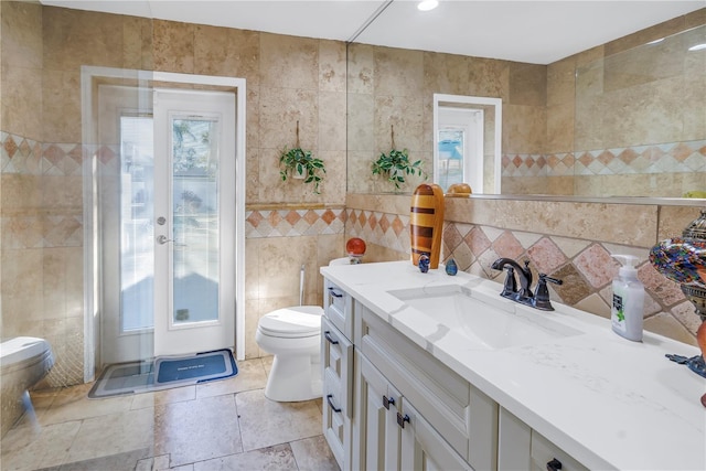 bathroom featuring vanity, toilet, and tile walls