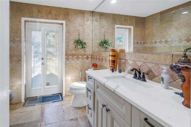 bathroom with vanity, toilet, and tile walls