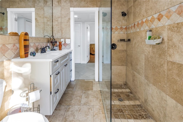 bathroom featuring decorative backsplash, tiled shower, vanity, and tile walls