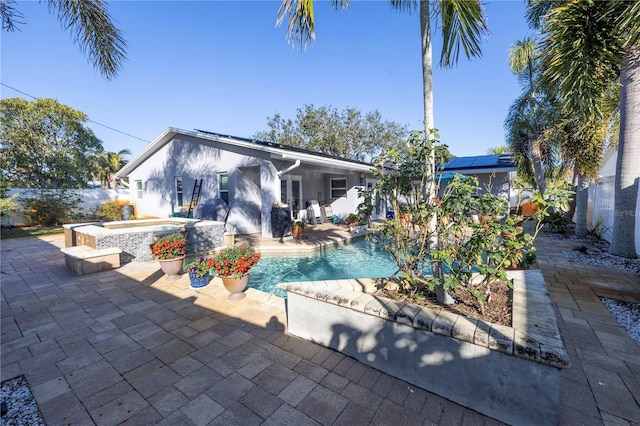 back of house with a patio area, a pool with hot tub, and solar panels