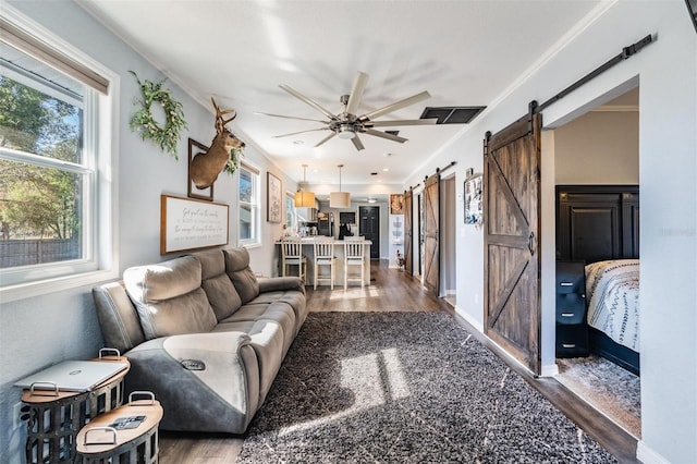 living room with hardwood / wood-style flooring, crown molding, a barn door, and ceiling fan