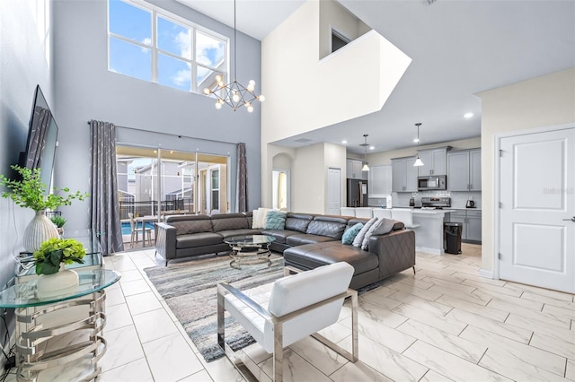 living room featuring a notable chandelier, a healthy amount of sunlight, and a towering ceiling