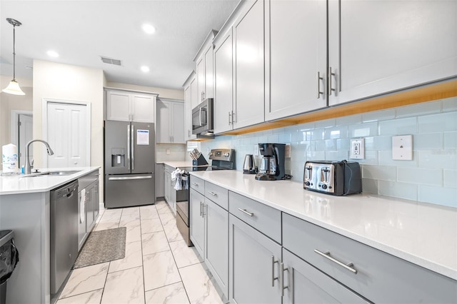 kitchen with backsplash, sink, hanging light fixtures, gray cabinets, and stainless steel appliances