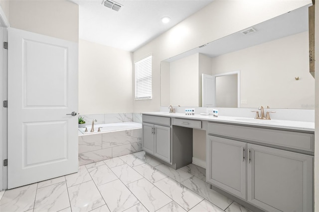 bathroom featuring vanity and tiled bath