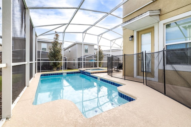 view of pool with glass enclosure, an in ground hot tub, and a patio