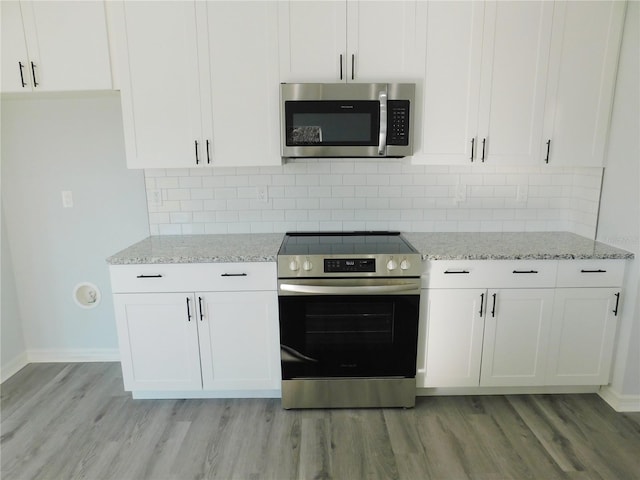 kitchen with white cabinets, decorative backsplash, light stone countertops, and appliances with stainless steel finishes