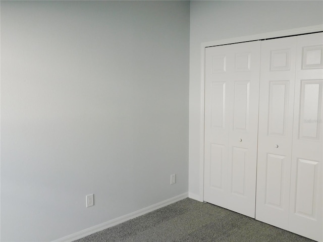 unfurnished bedroom featuring dark colored carpet and a closet