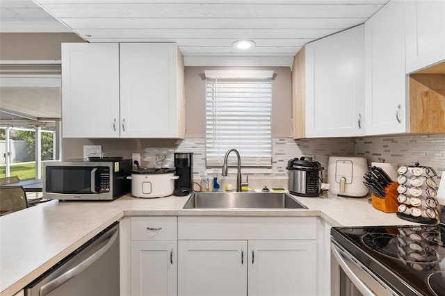 kitchen featuring decorative backsplash, white cabinetry, sink, and appliances with stainless steel finishes