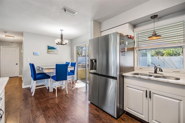 kitchen featuring stainless steel fridge with ice dispenser, sink, white cabinets, and hanging light fixtures