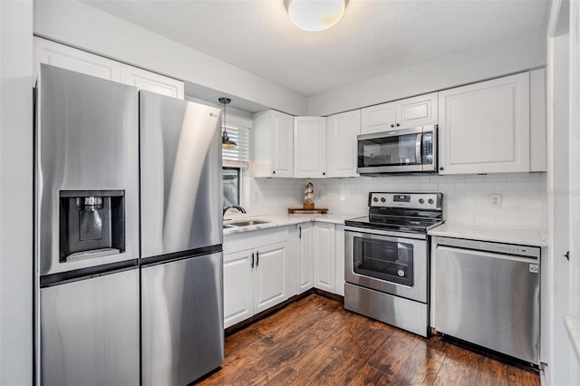 kitchen featuring white cabinetry, sink, dark wood-type flooring, stainless steel appliances, and decorative backsplash