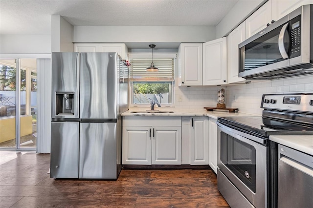 kitchen with sink, white cabinetry, stainless steel appliances, and hanging light fixtures