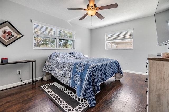 bedroom featuring ceiling fan, dark wood-type flooring, and multiple windows