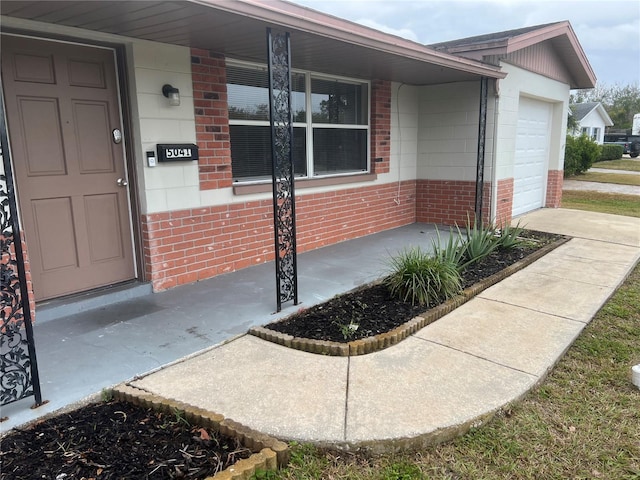 view of exterior entry with a garage and a porch