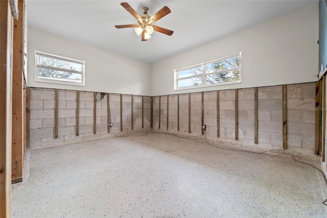 basement with ceiling fan and a wealth of natural light