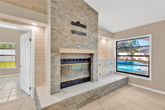 unfurnished living room featuring vaulted ceiling, a fireplace, and light tile patterned floors