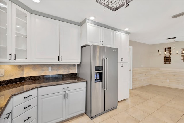 kitchen featuring dark stone countertops, high quality fridge, hanging light fixtures, and white cabinetry