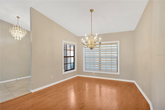 unfurnished dining area with light wood-type flooring, vaulted ceiling, and a notable chandelier