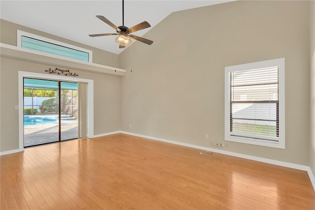 empty room with high vaulted ceiling, ceiling fan, and light wood-type flooring