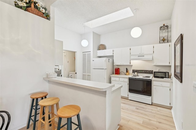 kitchen with white appliances, a breakfast bar area, hanging light fixtures, a skylight, and white cabinetry