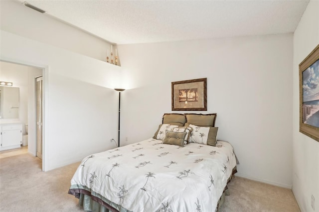 bedroom featuring ensuite bath, a textured ceiling, vaulted ceiling, and light colored carpet