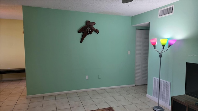 spare room featuring light tile patterned flooring and a textured ceiling