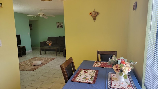 tiled dining space with a textured ceiling and ceiling fan