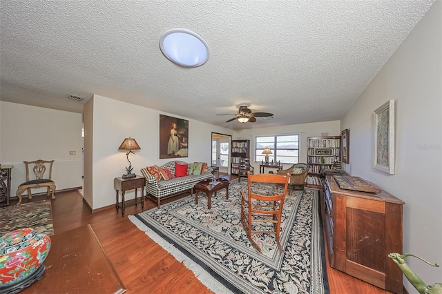 living room with hardwood / wood-style flooring, a textured ceiling, and ceiling fan