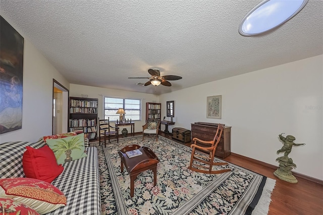 living room featuring ceiling fan, hardwood / wood-style flooring, and a textured ceiling