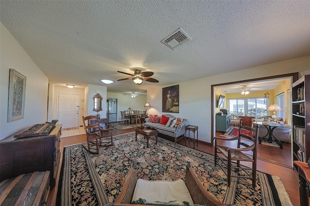 living room featuring ceiling fan and a textured ceiling