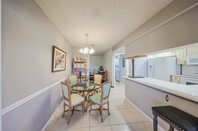 tiled dining room with a chandelier, a textured ceiling, and washer / dryer