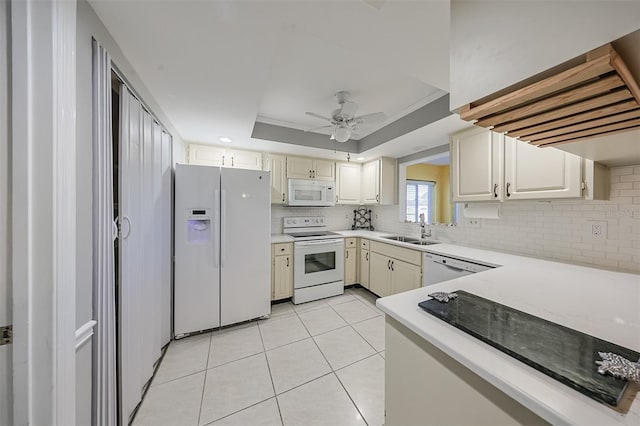 kitchen with sink, light tile patterned floors, ceiling fan, a tray ceiling, and white appliances